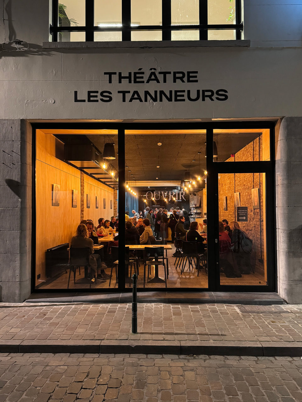 Vue du Resto des Tanneurs depuis l'extérieur, le soir. Il y a du monde à l'intérieur.