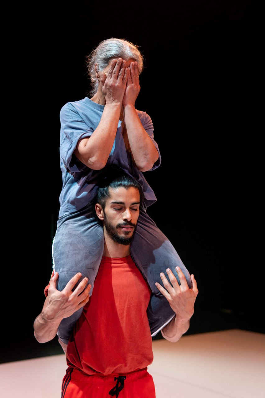 Le danseur et sa maman sont sur scène. Il porte sa maman sur ses épaules.
