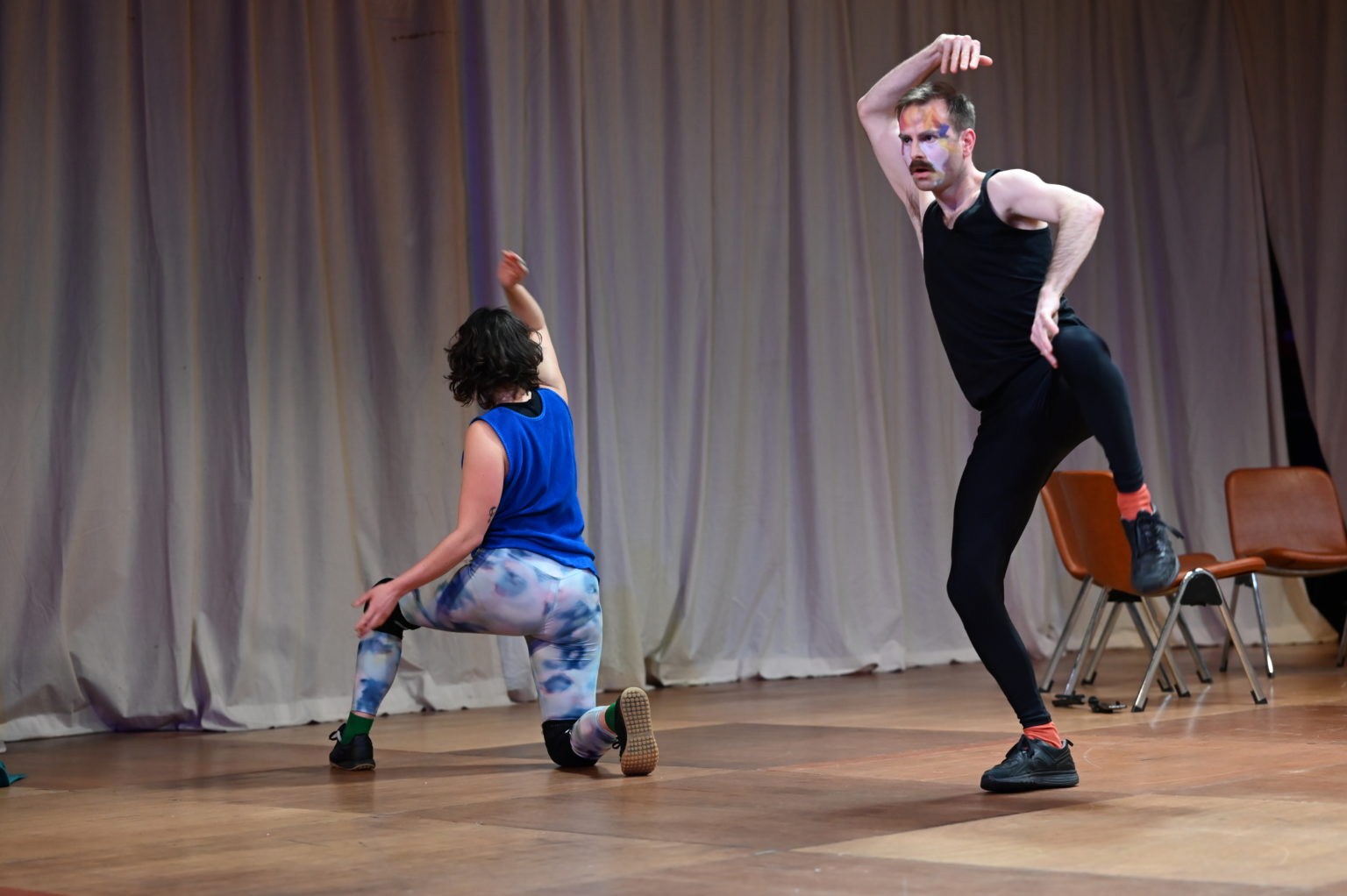 Les deux comédiens (Cédric Coomans et Chloé Larrère) dansent et font des gestes étranges. Ils portent des leggings et des débardeurs.