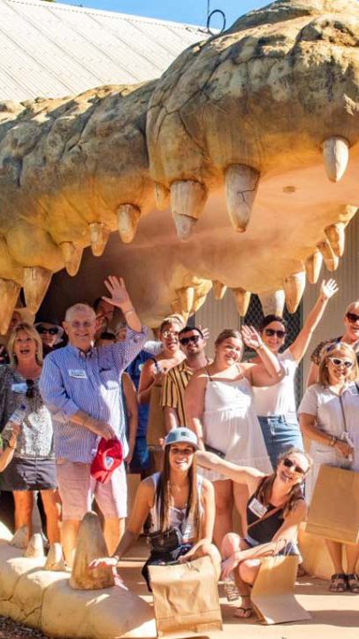 Un groupe de personnes posent devant la caméra avec les bras levés. Ils sont dans la bouche d'un grand crocodile.